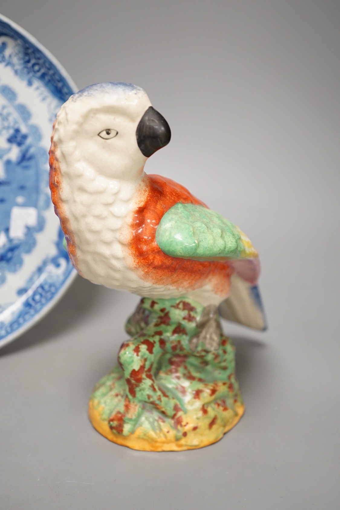 A Staffordshire pottery figure of a parrot, 19.5cm tall, together with a blue and white dish